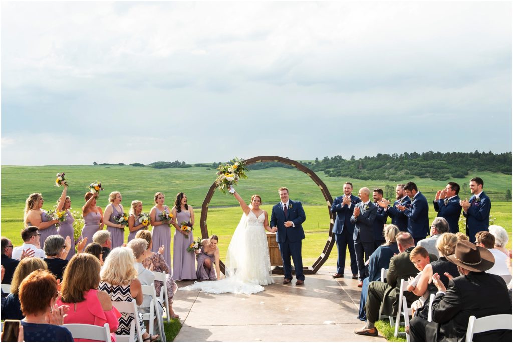 wedding party and guests celebrate with the bride and groom in this outdoor summer wedding