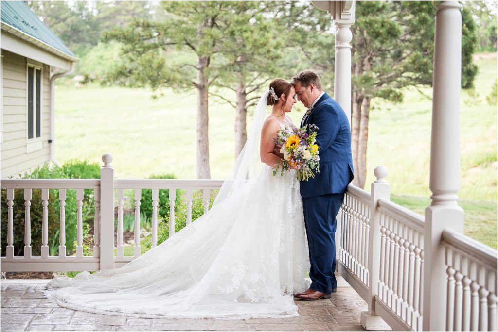 wedding photo captures a private moment between the bride and groom on the front porch of Flying Horse Ranch