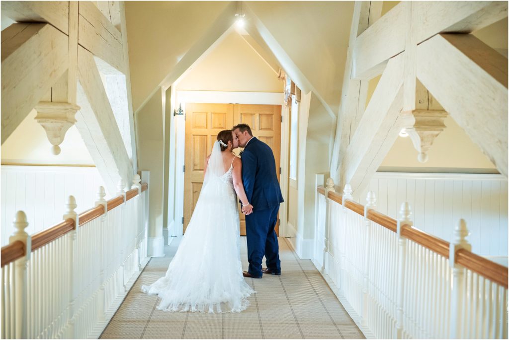 White beams and a kiss on the catwalk at Flying Horse Ranch create a magical wedding photo