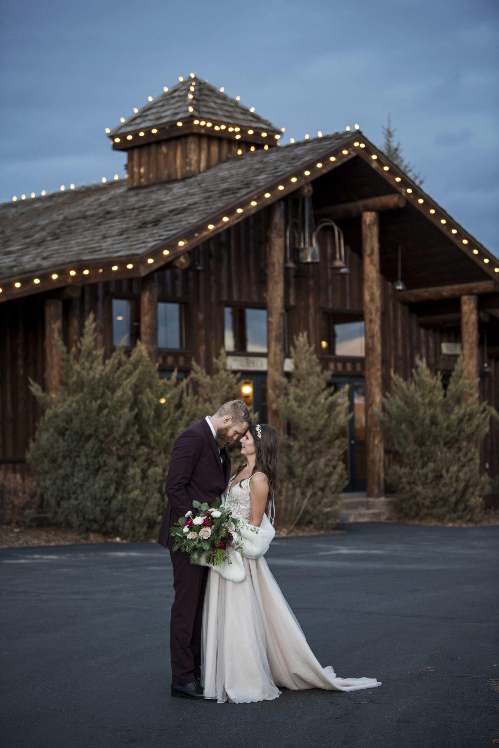 Bride and groom stand holding each other outside of Albert's Lodge at Spruce Mountain Ranch