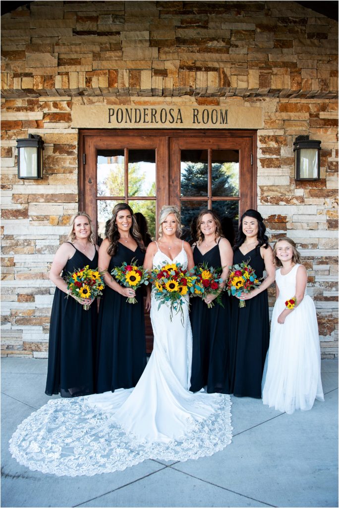 Bride and bridesmaids stand together with sunflower bouquets