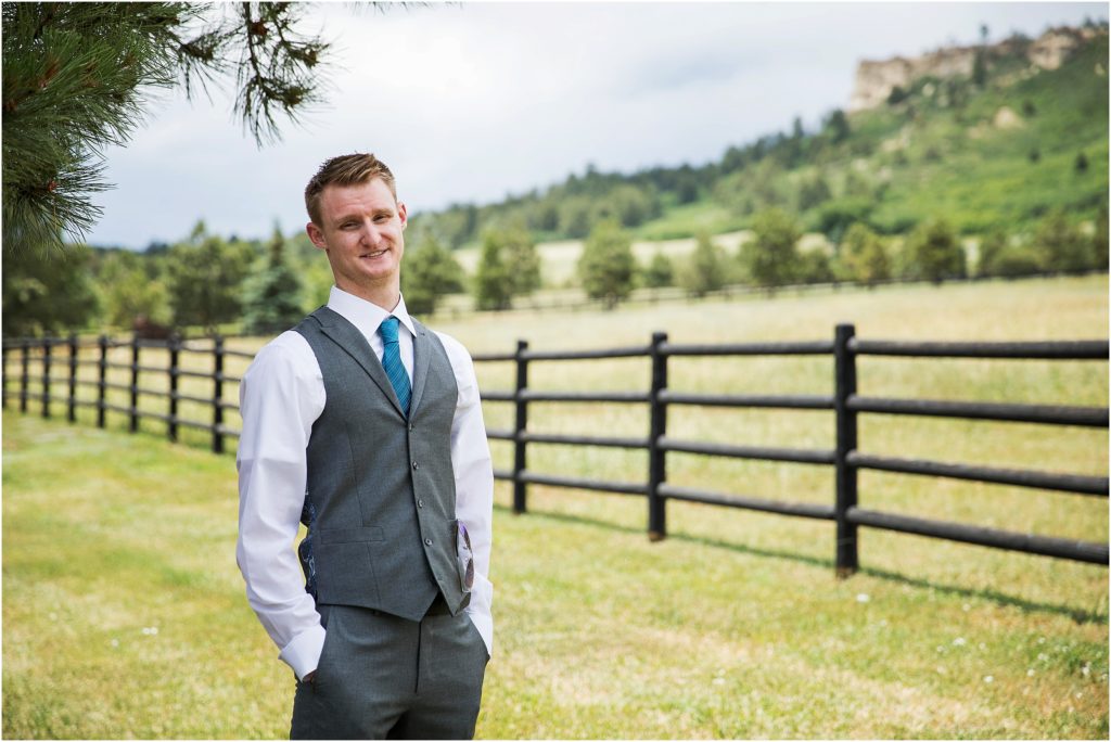 Groom wears grey vest and teal tie with dark blue accents