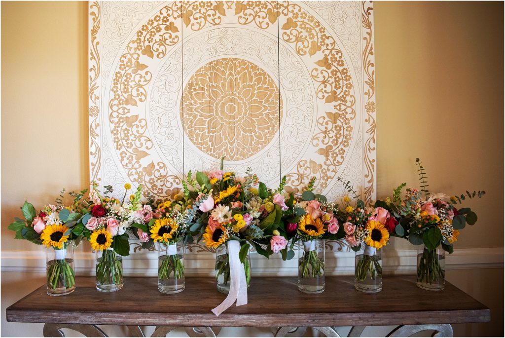 Wedding bouquets with sunflowers and roses sit on a table in a row