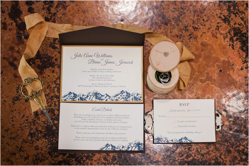Blue white and gold wedding invitation laid out with gold silk ribbon and wedding rings