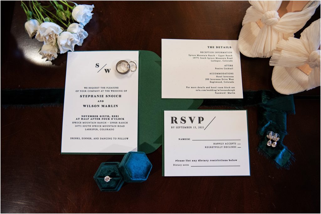 wedding invitation and bride details lay out on a table with florals