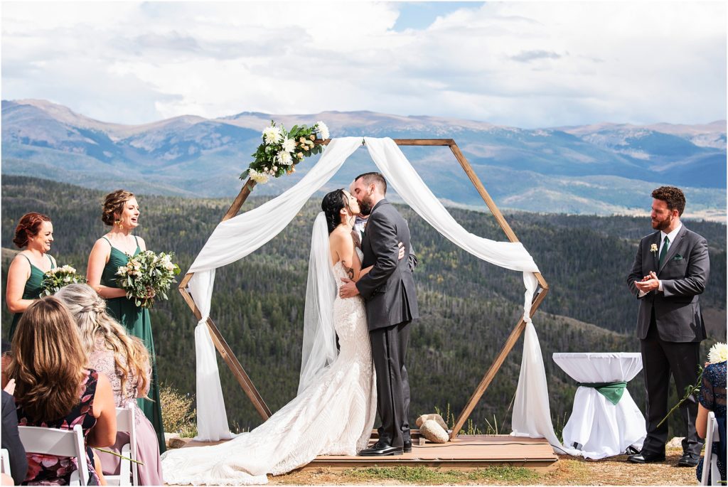 Bride and groom kiss on top of a mountain at the end of their mountaintop ceremony in Colorado