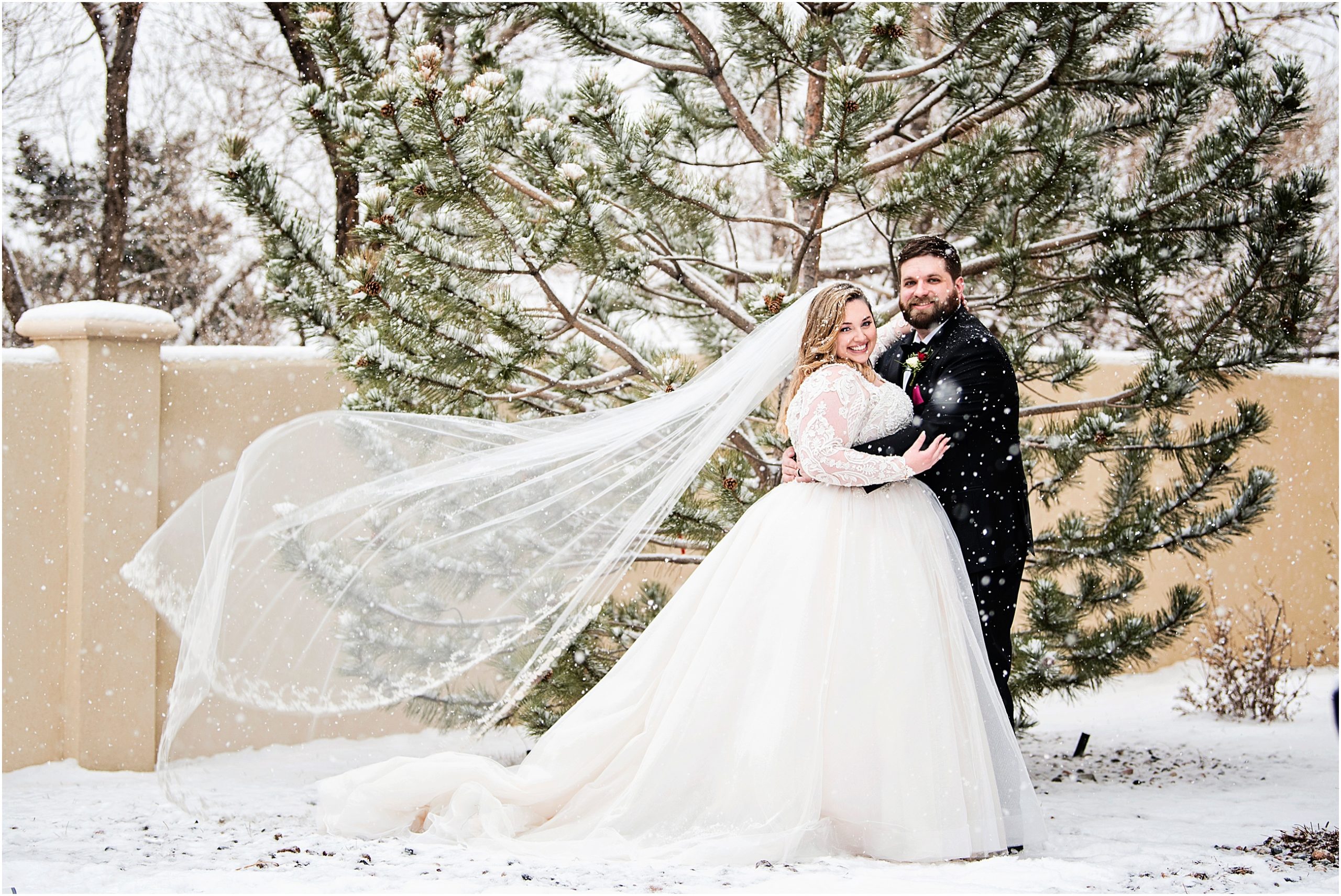Brides veil flies while she is embracing her husband on their wedding day in the snowy colorado weather