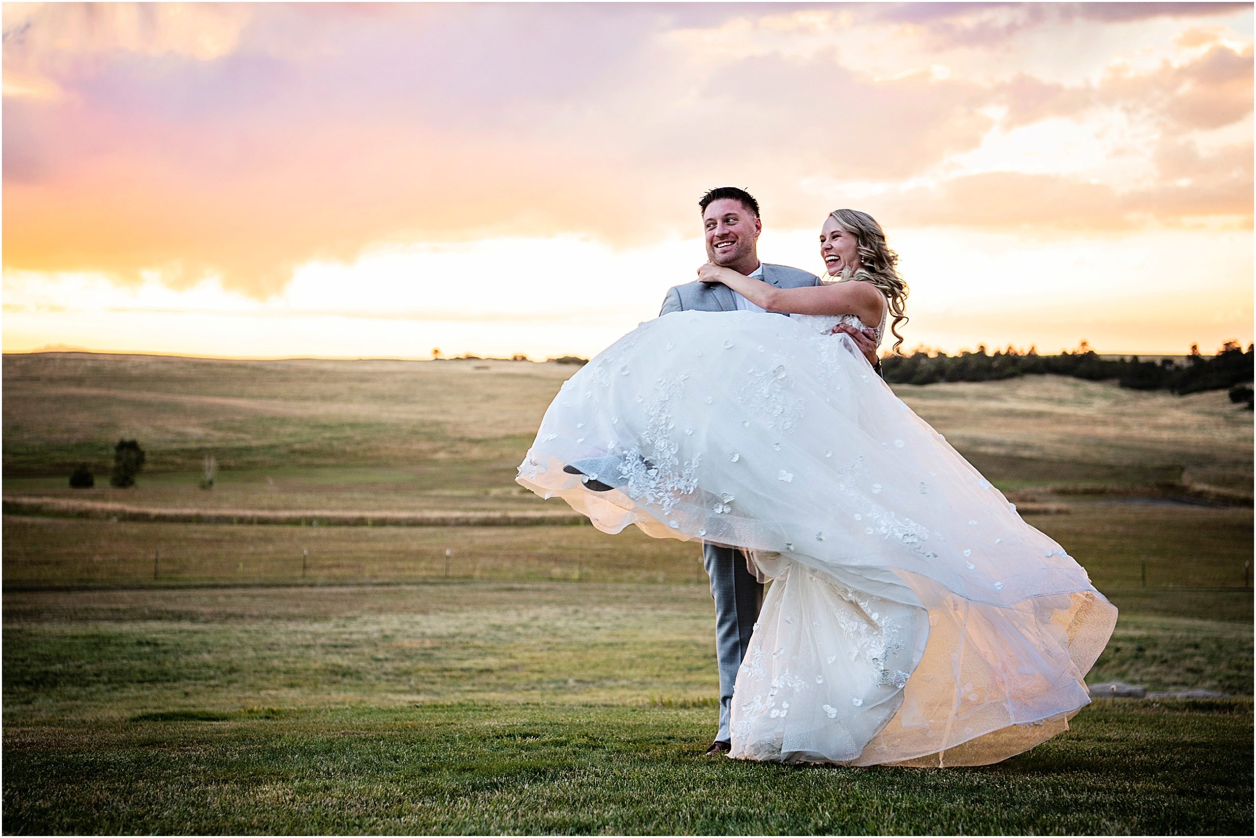 Groom carries bride at sunset while they Bothe smile and laugh